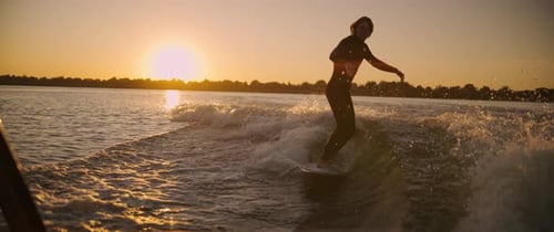 A Surfer Captivates the Splendor of Sunset Waves Gliding Gracefully Across the Water While Embracing