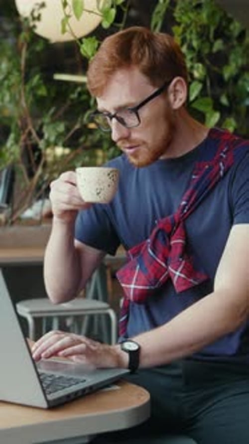 Young Man Working on Laptop at Cafe