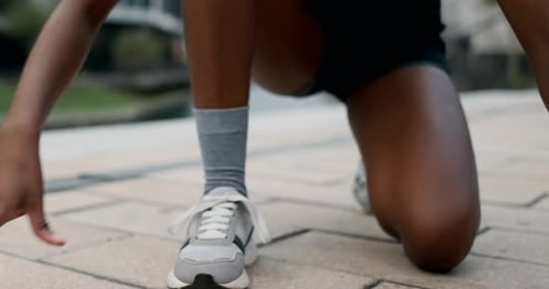 Person Tying Shoe on Urban Sidewalk