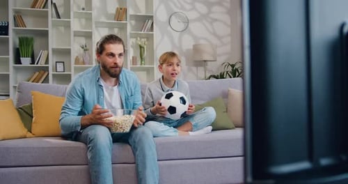 Father and Son Watching Sports Game at Home