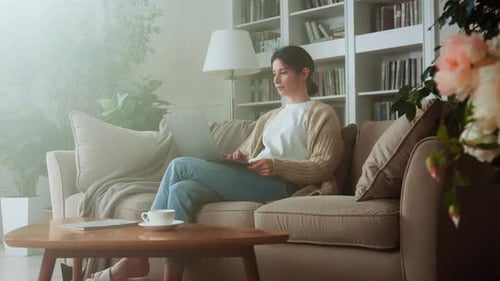 Woman Using Laptop on Sofa at Home