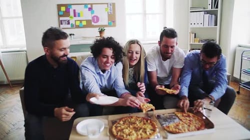 Group of Young Businesspeople with Pizza Having Lunch in a Modern Office