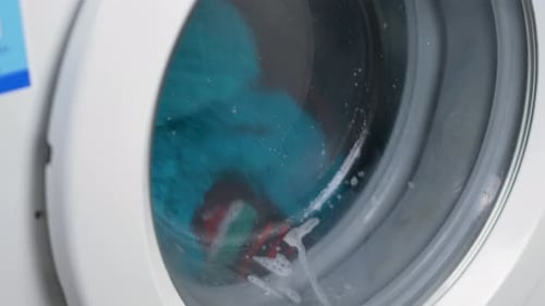Close up slow motion shot of washing machine with cotton towels spinning cleaning water wet househol