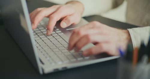 Businessman Tying on Laptop at Desk in Office