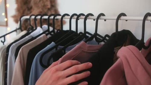 Hand Browsing Clothes on a Clothing Rack