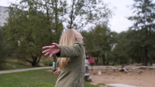 Happy Little Girl Spinning in Summer Park on Playground