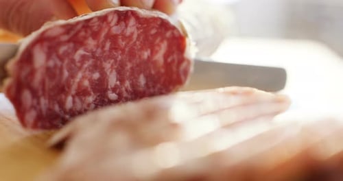 Slicing Cured Sausage on Wooden Cutting Board