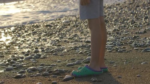 Waves on Pebbled Beach During Sunset Creative Vacation Concept Side View of a Boy Legs Standing at