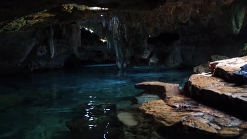 Tilt up shot of a beautiful underground Mexican Cenote with Stalactites growing from the roof and cr