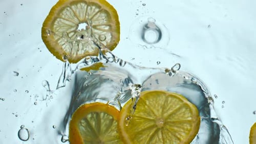 Lemon Slices Falling Into Water With Bubbles