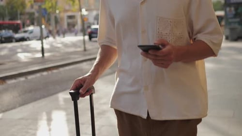 Young Man Walking to the Airport Pulling Suitcase Baggage Use His Phone with Voice Recognition Audio
