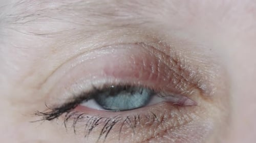 Macro close up turquoise blue human eye blinking and staring at camera