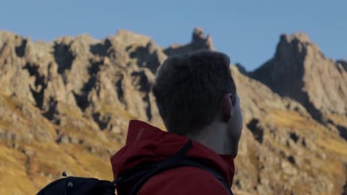 Close up tracking shot of male hiker enjoying beautiful mountain landscape during Sunny day and blue