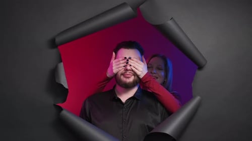 Man Surprised by Woman Covering Eyes Through Torn Paper