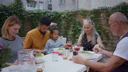 Family Holding Hands Before Meal in Backyard