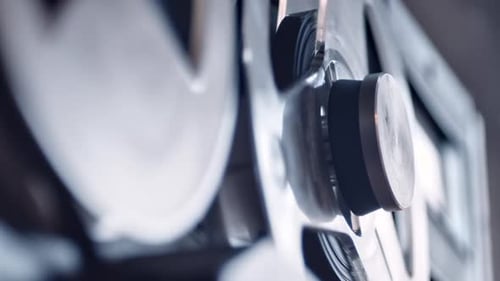 Tape recorder playing crime evidence on magnetic deck, closeup side view