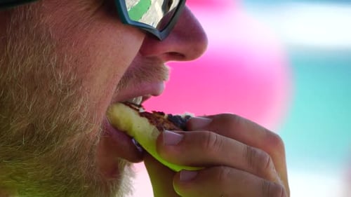 Mann isst Käsekuchen Bärtiger Mann mit Sonnenbrille isst Käsekuchen am Strand Glücklicher Mann lächelt
