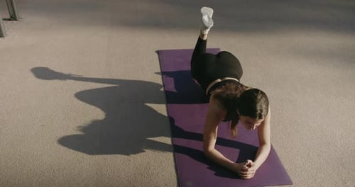 Woman Exercising with Resistance Band on Mat Outdoors