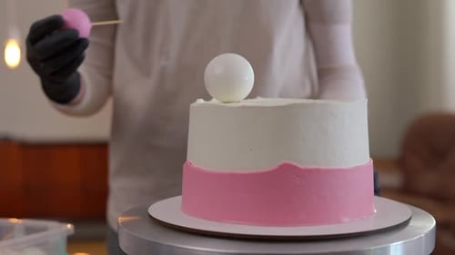 Cake Decorator Placing Spherical Candy Decorations
