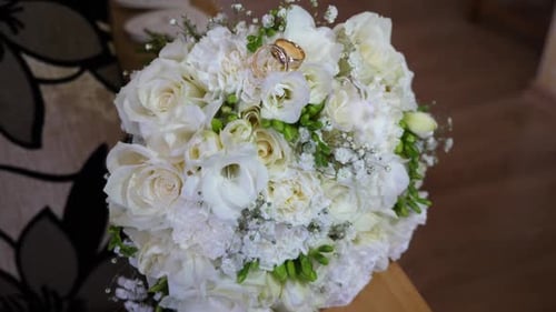 32/ Two gold wedding rings on a beautiful white wedding bouquet.