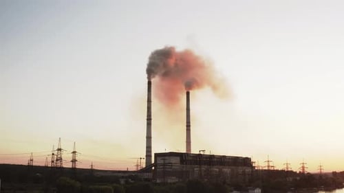 En Static view of the high-voltage tower sky background, factory pipe with smoke over it.
