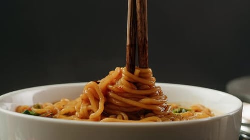 Close Up of Noodles Being Lifted by Chopsticks