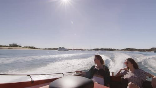 Deux belles jeunes femmes portant des lunettes de soleil en croisière sur un bateau à moteur près de