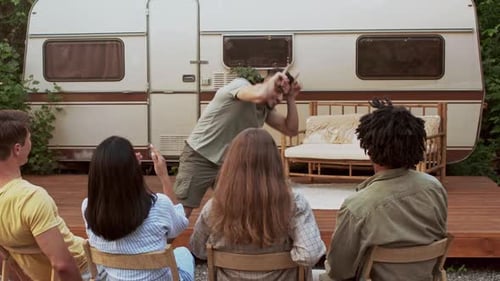 Friends Play Charades Outside Near Campervan