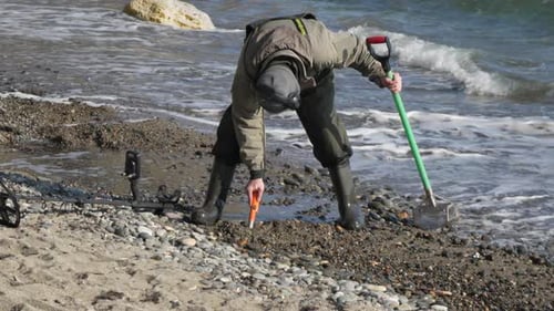 Metal Detecting Beachcombing Treasure Man Digs Treasure with Metal Detector on Beach During Daytime