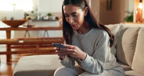 Woman Using Smartphone Relaxing on a Couch
