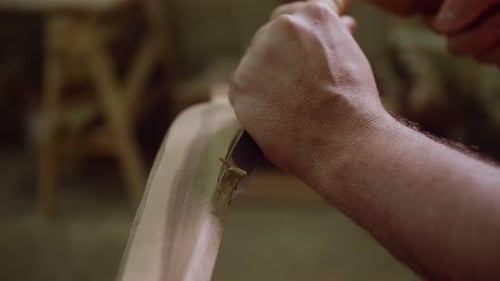 Woodworker Shaping Piece of Wood with Hand Tool
