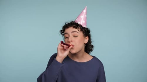 Close Up Happy Curly Woman in Birthday Cap Blowing Whistle Celebrating Holiday