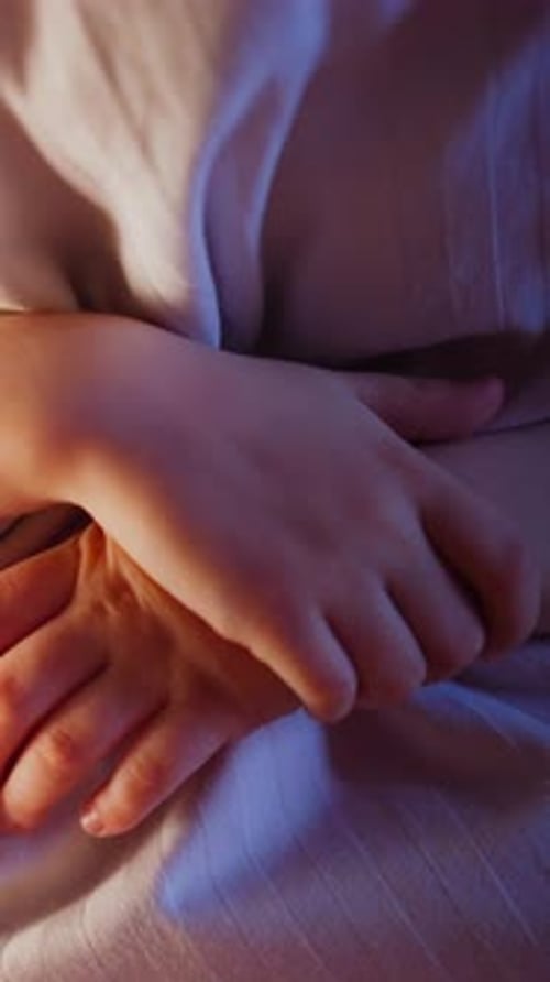 Little Kid Hugs Huge Soft Striped Pillow in Semidark Bedroom