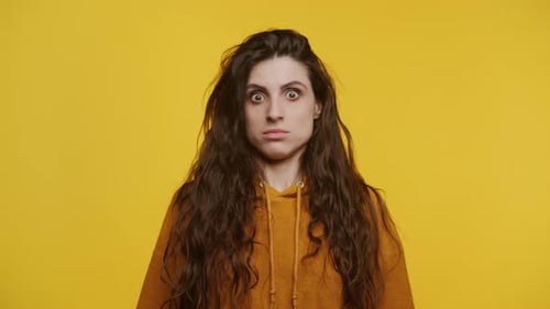 Woman Looks Shocked with Wide Eyes on Yellow
