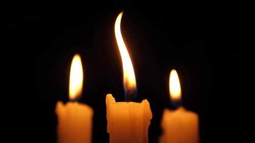 Three White Candles Flickering in the Darkness