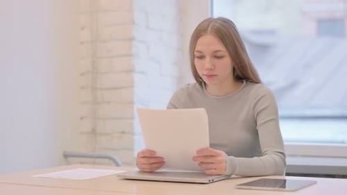 Woman Talking While Looking at Documents at Desk