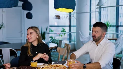 Friends Enjoying Pizza and Juice at Restaurant Table