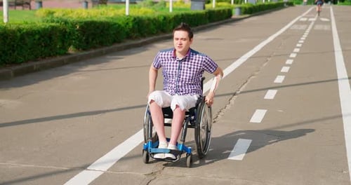 Young Adult in Wheelchair Outdoors on Paved Path