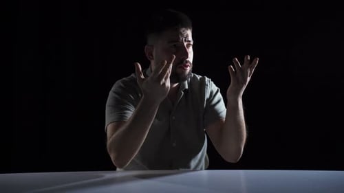 Man Talking and Gesturing at Dark Table