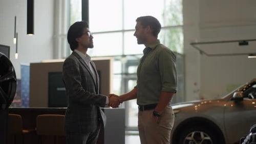 Side View of Young Customer Male Thanking Stylish Dealer Male Wearing Suit and Eyeglasses for