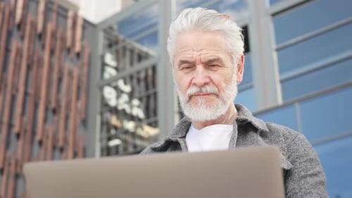 Mature Man Sitting on Bench and Holding Laptop Outdoors