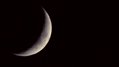 Close up of the waning crescent moon with craters visible slowly rotating - night time lapse