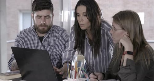 Three colleages working and collaborating on computer at the office