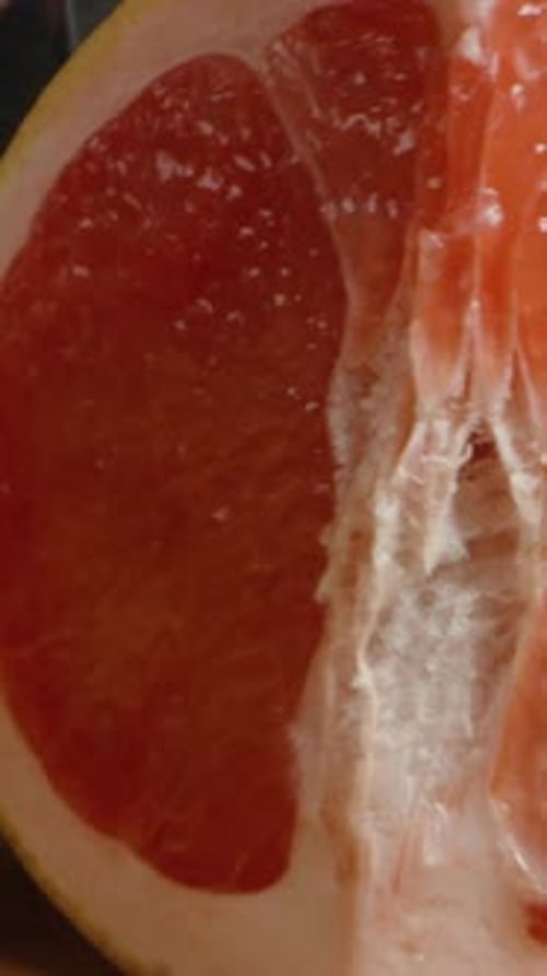 Vertical video. I cut the grapefruit into wedges. Dolly slider extreme close-up.
