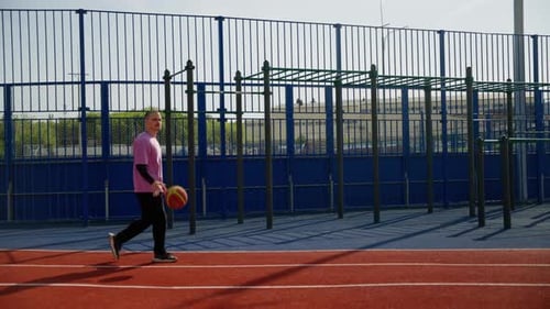 Man Walking and Bouncing Basketball at Recreational Space