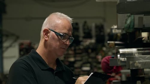 Supervisor Taking Notes During Quality Control in Factory