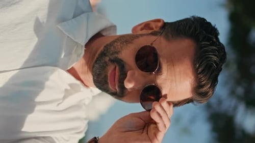 Vertical Portrait Smiling Hispanic Man Taking Off Sunglasses on Sunny Viewpoint