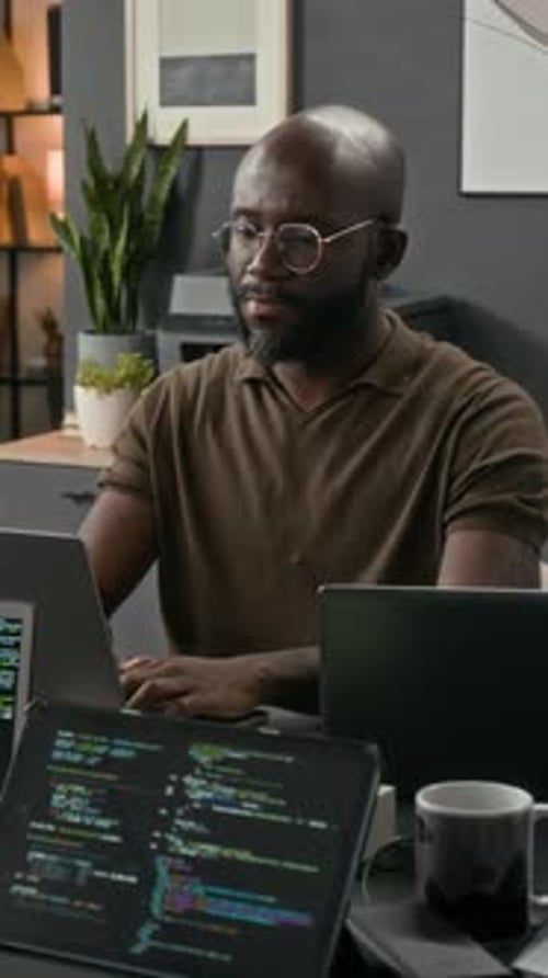 Man Works At Desk On Computer And Tablet