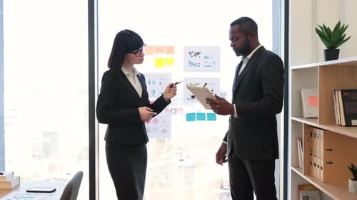 Businesspeople Discussing Graphs and Charts in Office Room