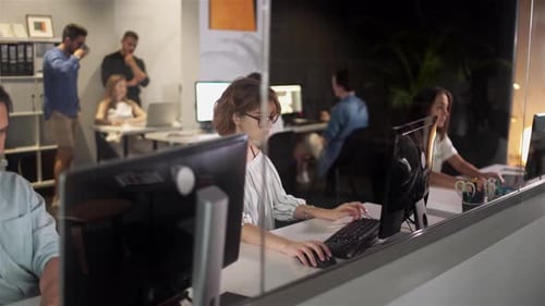 Workers Typing at Computers in Modern Office at Night